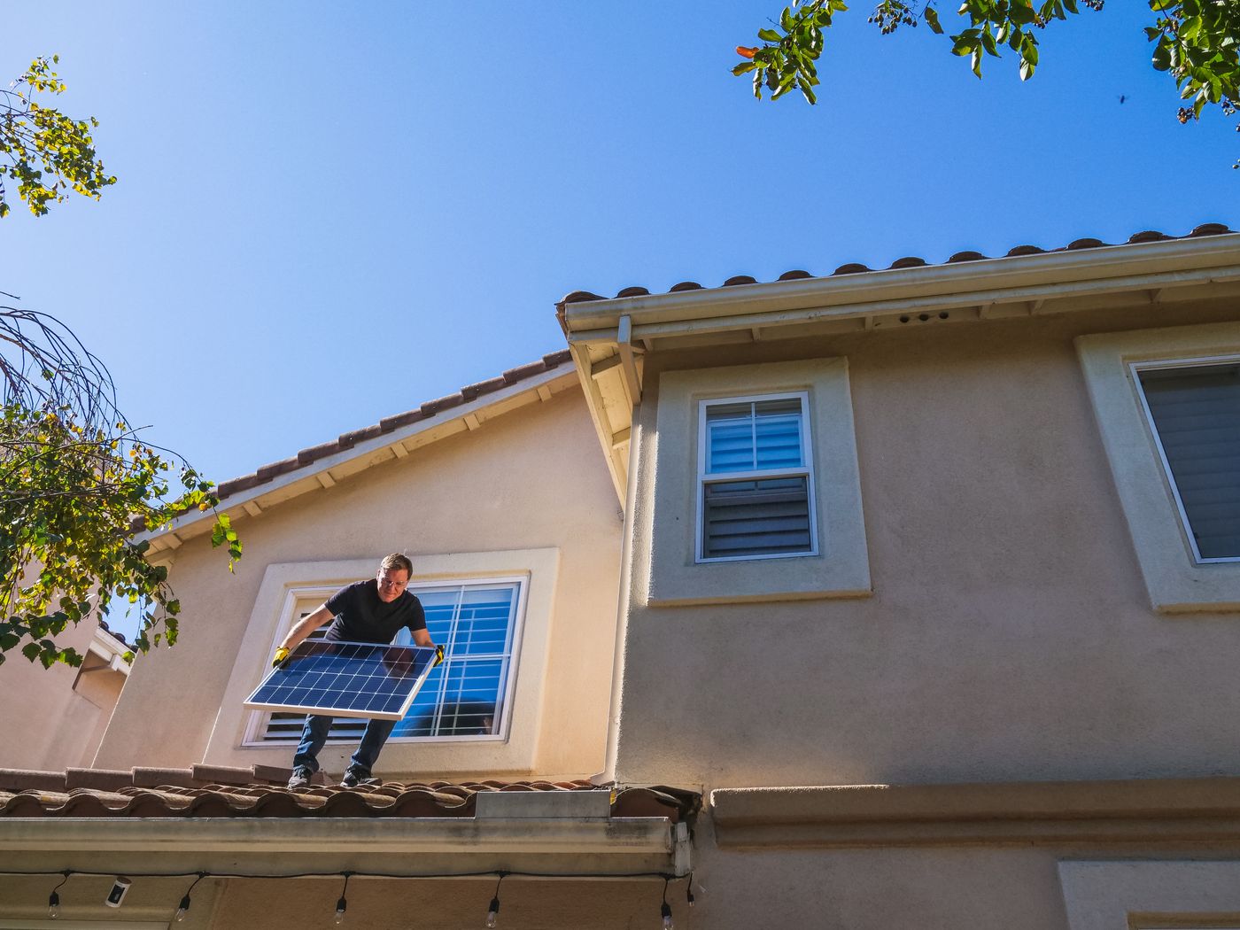 Homeowner installing solar panels on a residential rooftop